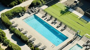 An aerial view of a swimming pool area with multiple lounge chairs and a grassy area. - El mejor departamento de Macul (Santiago)