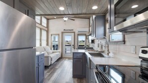 A modern kitchen with stainless steel appliances, a built-in oven, and a window overlooking the city. - Luxury Das Blumenhaus (Fredericksburg)