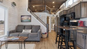 A modern kitchen with wooden cabinets, a stainless steel refrigerator, and a bar area. - There’s No Lookin’ Bach (Fredericksburg)