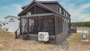 A two-story house with a covered porch and a large air conditioning unit in front. - There’s No Lookin’ Bach (Fredericksburg)