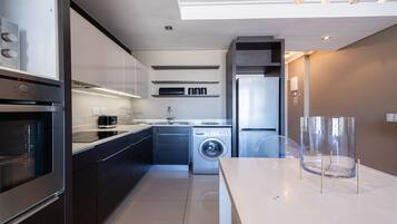 A modern kitchen with a built-in oven, a washing machine, and a dishwasher.