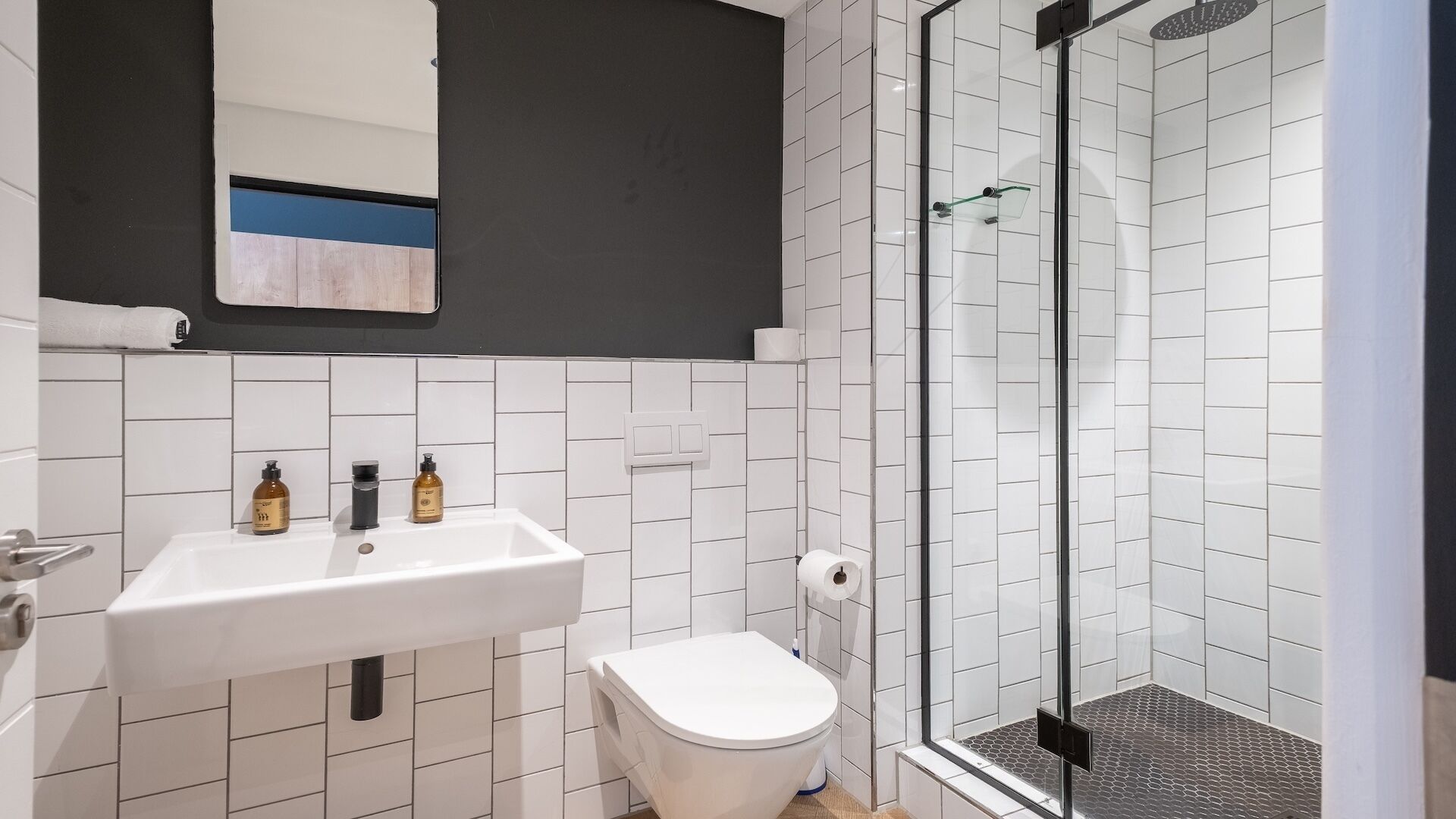 Een badkamer met een witte wastafel, toilet en douchecabine met glazen wanden.