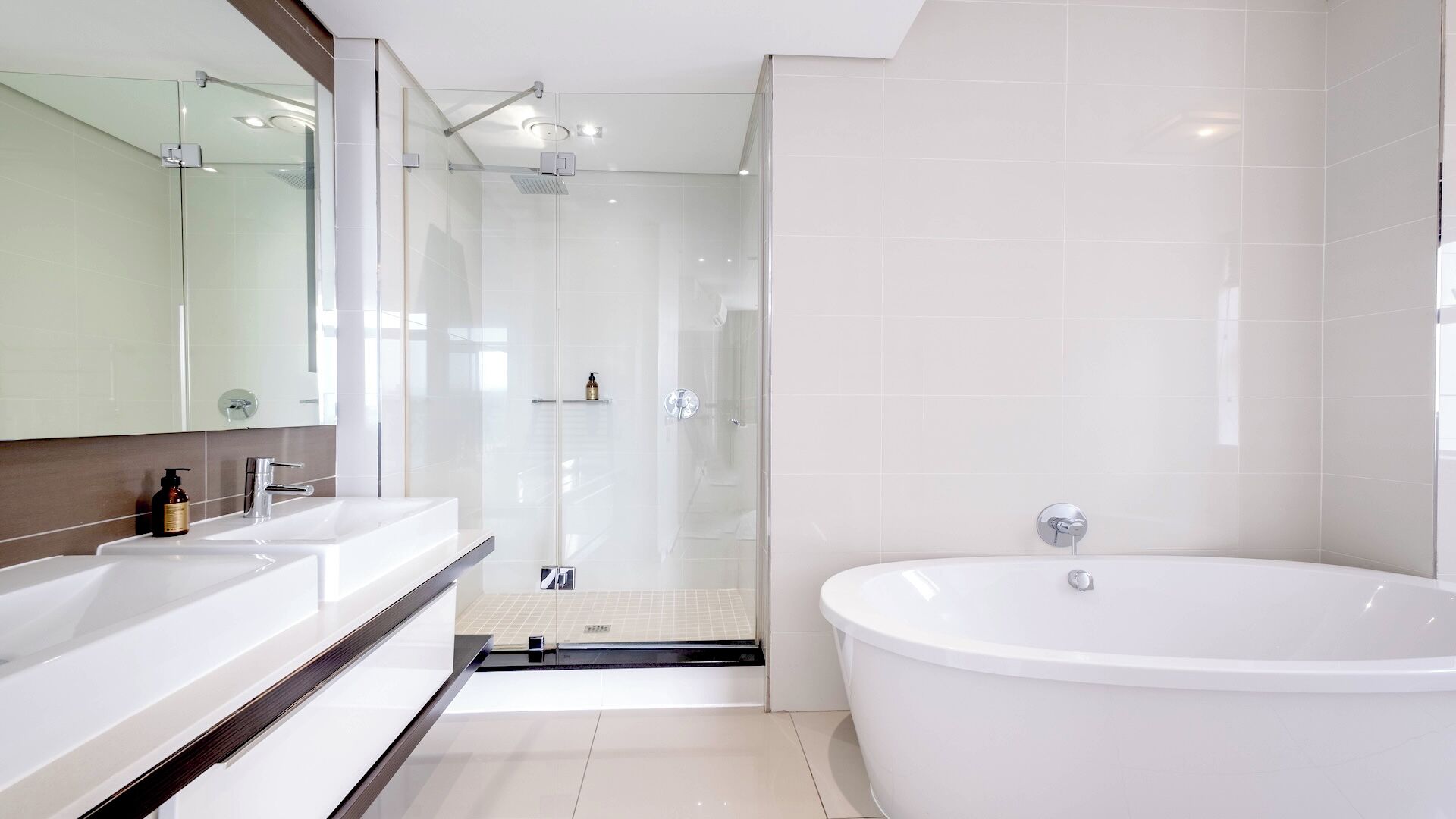 A modern bathroom with a glass shower enclosure, a freestanding bathtub, and a dual sink vanity.