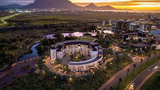 A hotel with a circular layout, surrounded by greenery and a river.