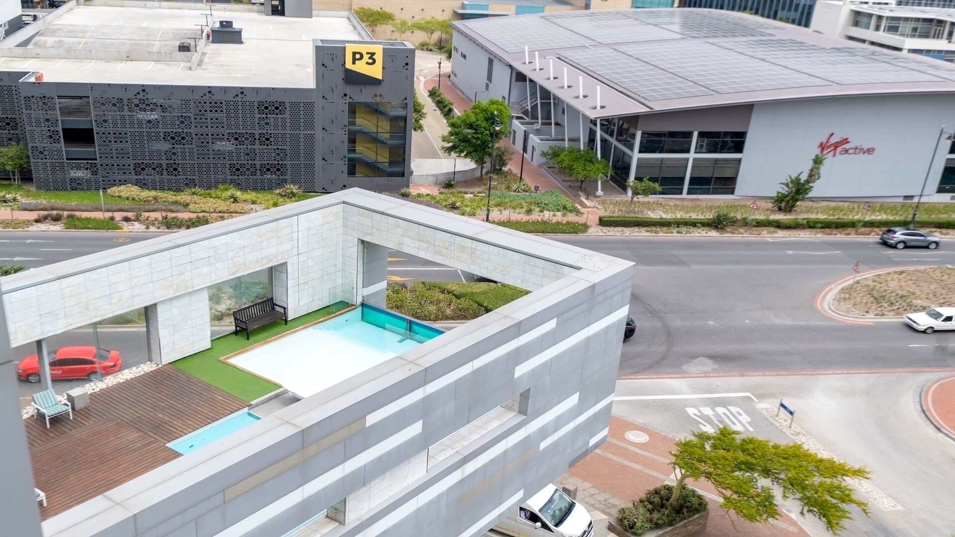 Un edificio moderno con piscina en la azotea, zona de estacionamiento y un cartel que indica P3.