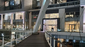 A modern building with a wooden walkway and glass railings.
