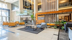 Un'ampia hall con arredi moderni, una scala in vetro e un'area bar.