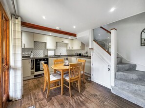 Eine moderne Küche mit weißen Schränken, einem Holzespeisetisch und einer Treppe, die zu einer zweiten Etage führt.
