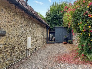 A stone building with a gravel driveway, a wooden door, and a sign reading "ILSBURY". - 2 bedroom accommodation in Combe Raleigh (Combe Raleigh)
