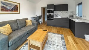 Una sala de estar moderna con un sofá gris, una mesa de centro de madera y un cuadro en la pared.