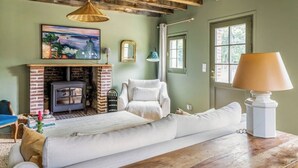 Una sala de estar acogedora con chimenea, un sofá, una mesa de madera y una lámpara.