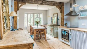 Una cocina rústica con vigas de madera, una mesa de comedor con sillas y un ventanal amplio.
