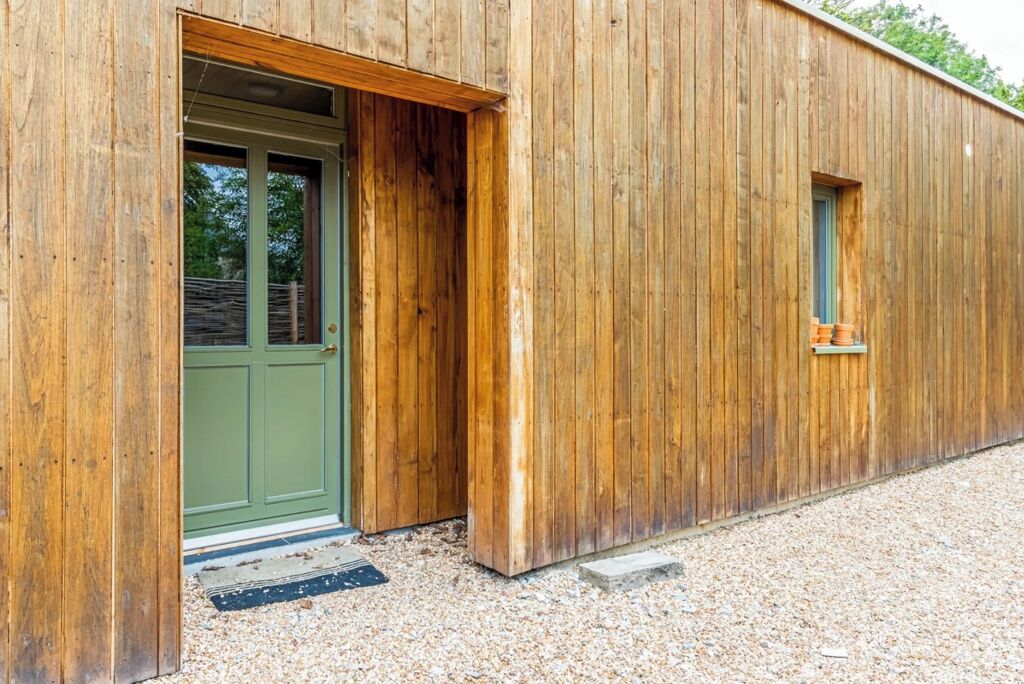 A wooden building with a green door and a small window.