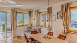 Ein Essbereich mit Holztisch, sechs Stühlen und einer Couch mit Kissen.