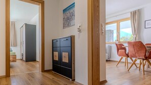 Ein modernes Wohnzimmer mit Holzboden, einem schwarzen Schrank mit Holzvertäfelung, einem Essbereich mit roten Stühlen und einem Fenster mit Blick.