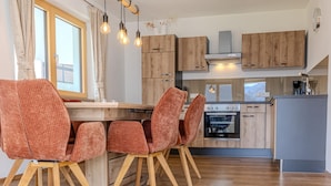Eine moderne Küche mit Holzausstattung, einem eingebauten Backofen und Pendelleuchten.