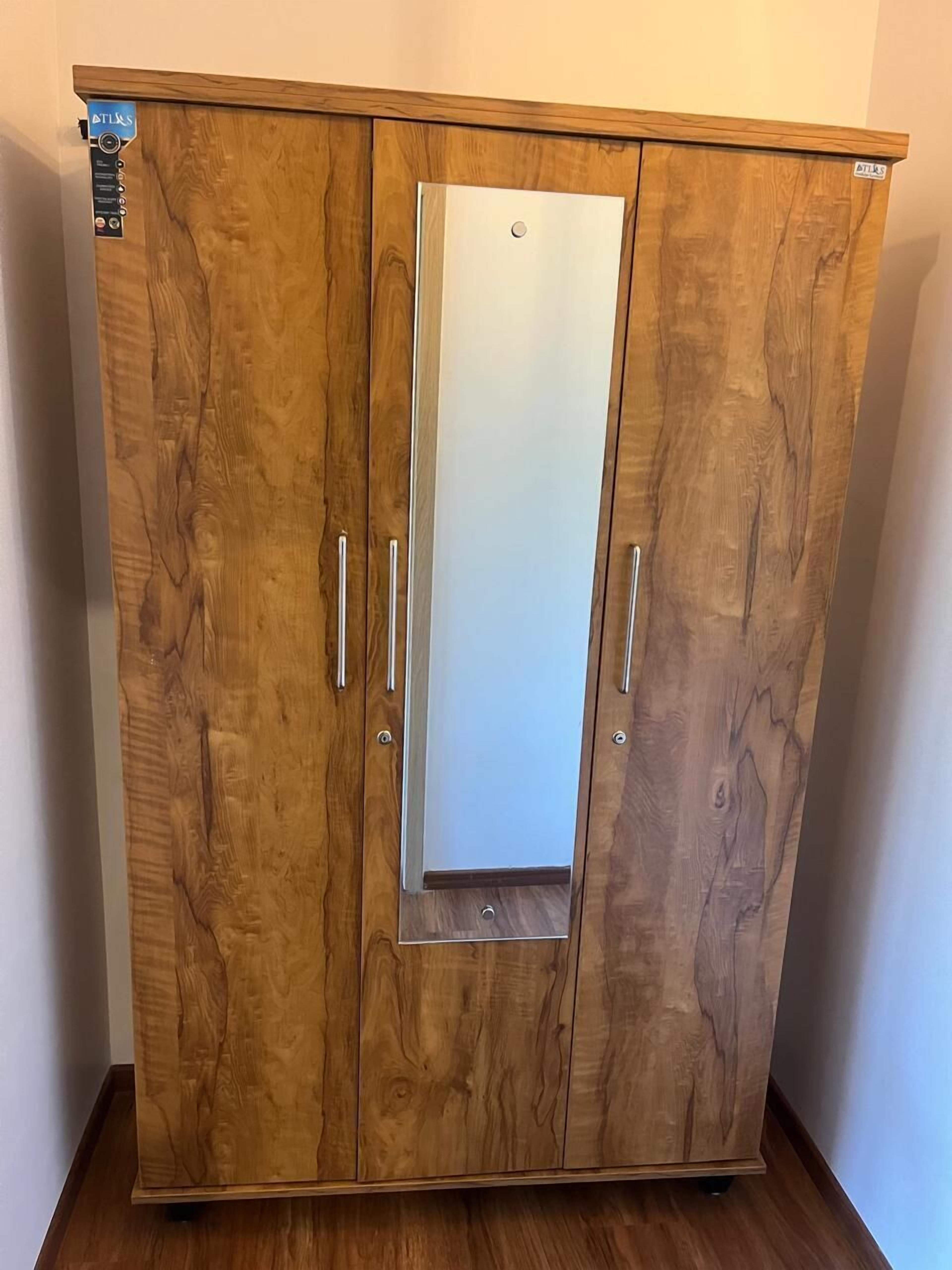 A wooden wardrobe with two doors and a mirrored panel.
