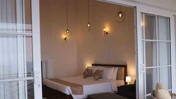 Un dormitorio con cama, mesitas de noche, una silla y lámparas colgantes.