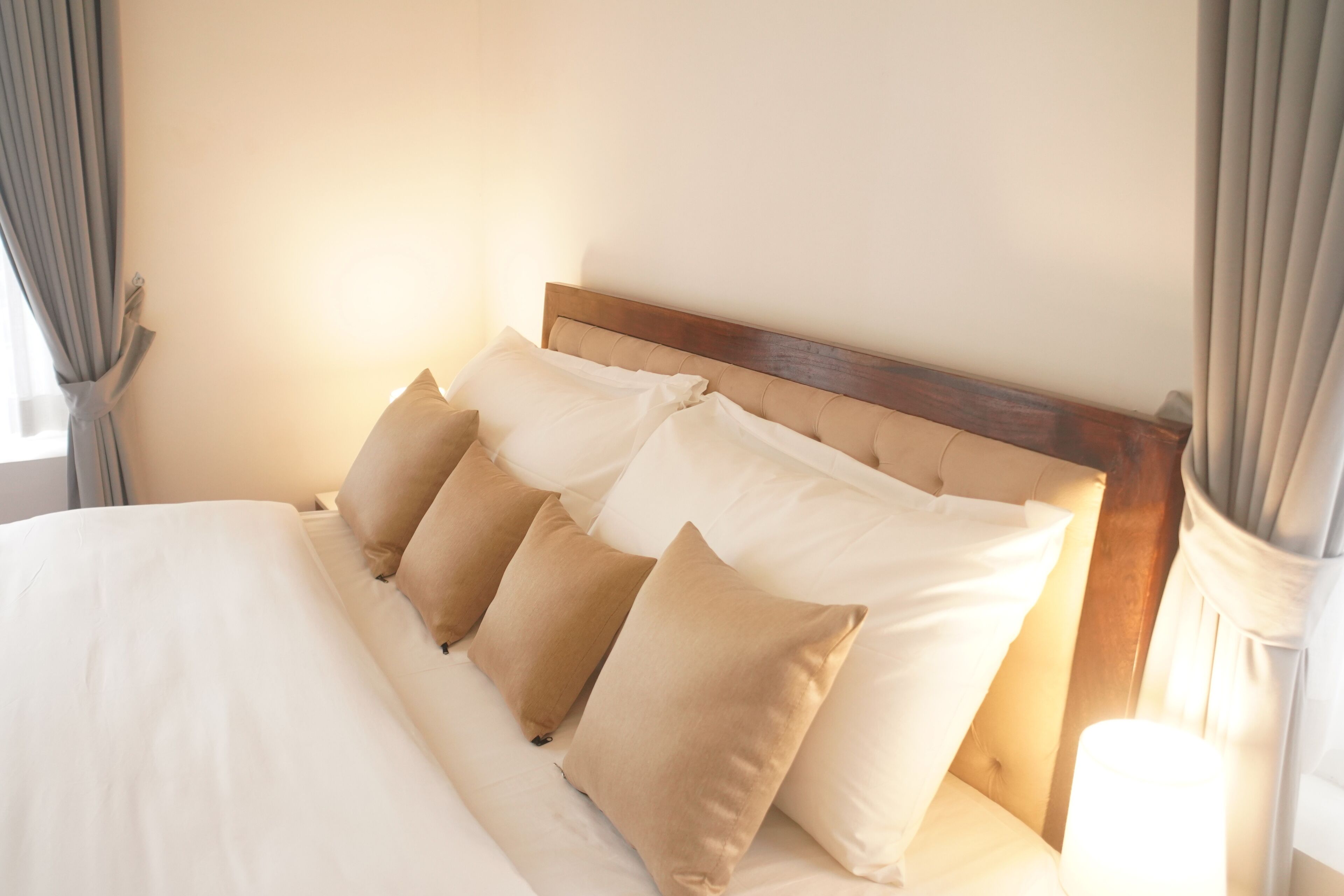 A neatly made bed with a wooden headboard and multiple pillows.