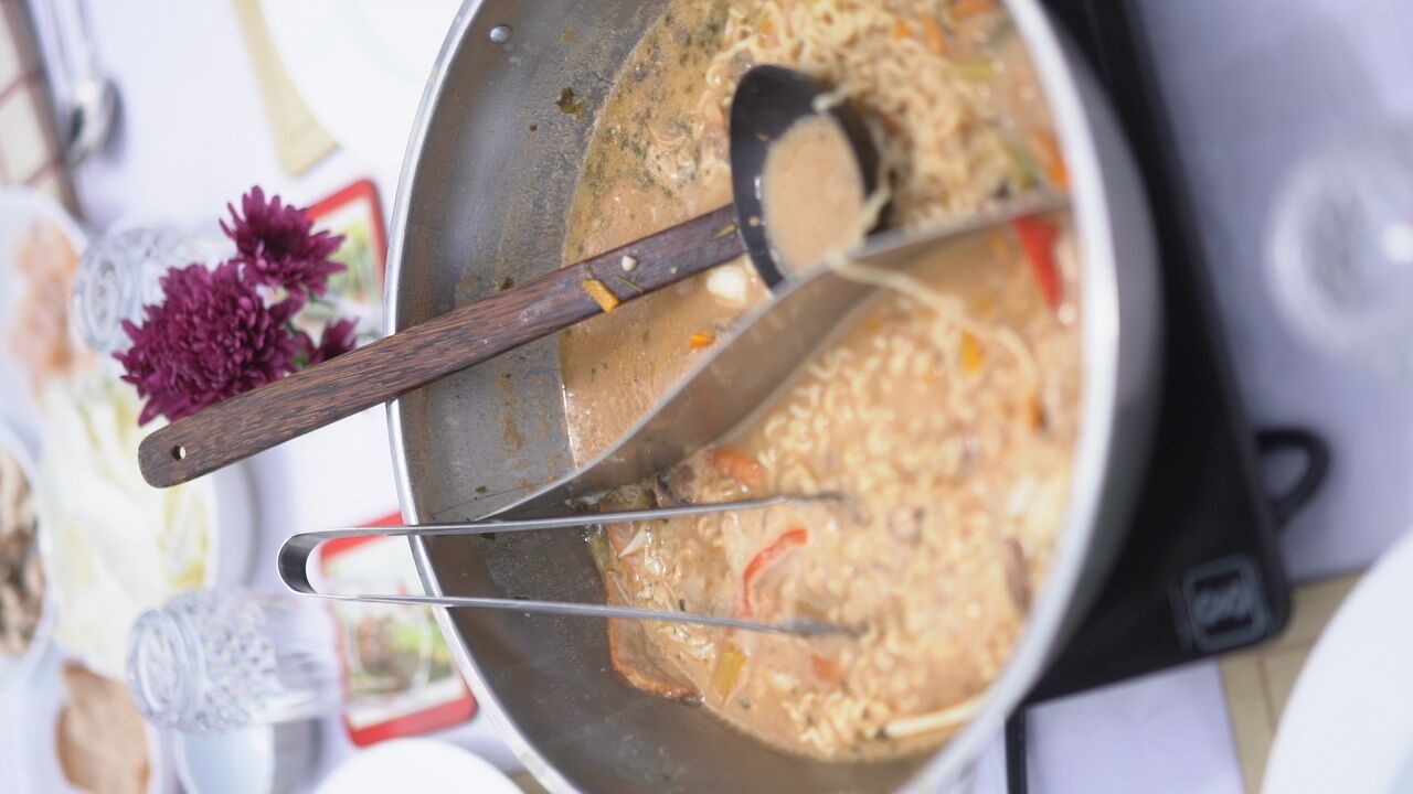 A cooking pot with a wooden handle on a stove.