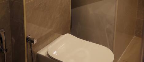 A modern bathroom with a white toilet, a sink, and a shower.