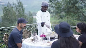 A person serving food outdoors with a table set for guests.