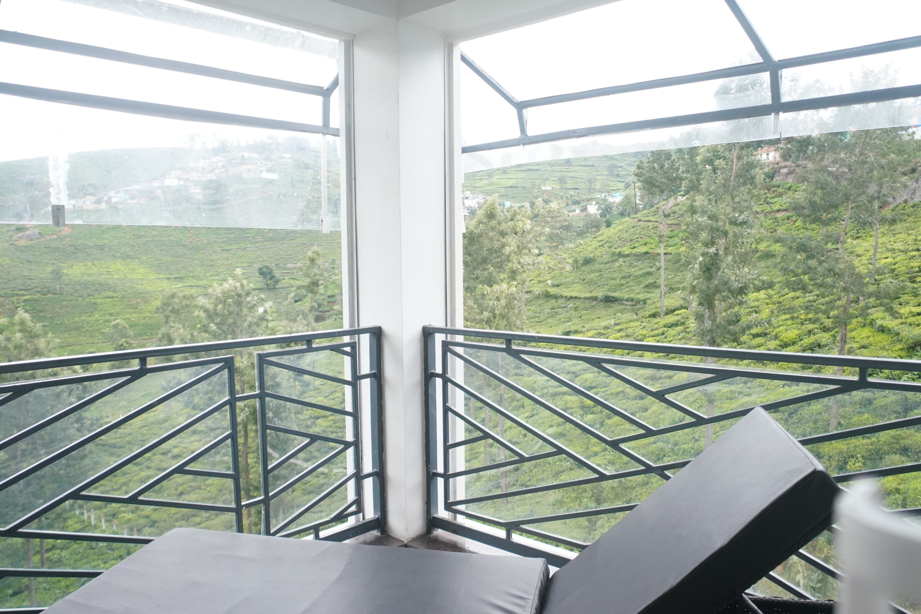 A balcony with a view of a green landscape, including terraced fields and trees.