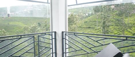 A balcony with a view of a green landscape, including terraced fields and trees.