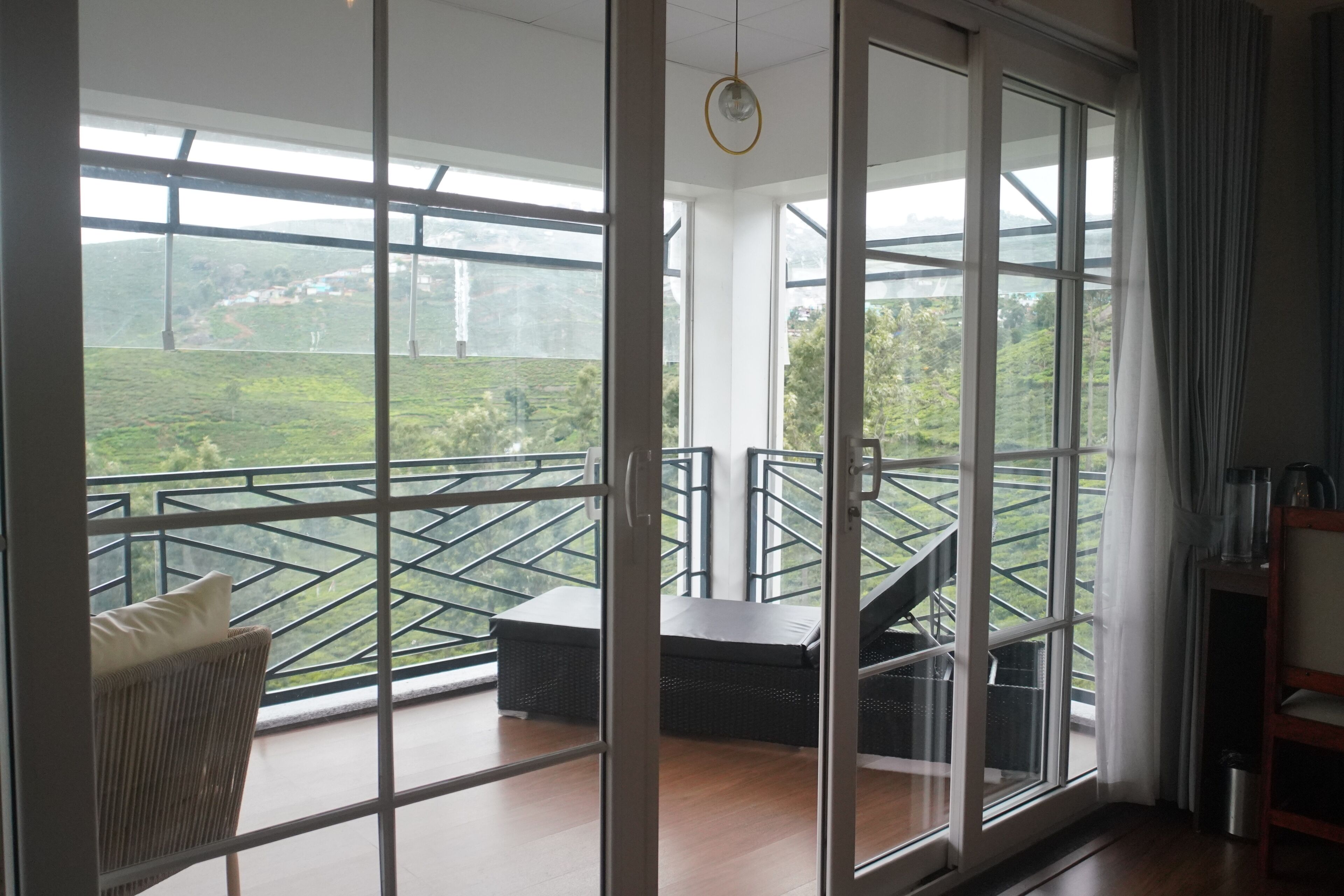 A room with a large sliding glass door leading to a balcony with a view of a green landscape.