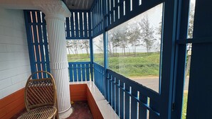 A covered porch with a view of a grassy area and trees. - KUZHUPPILLY BEACH HOUSE (Kochi)
