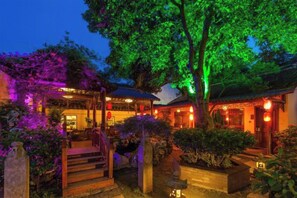 A traditional building with a staircase leading to a covered entrance, surrounded by greenery and illuminated by warm lighting. - Zhouzhuang Latte Play Stone Mulan Hotel (Kunshan)