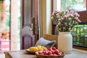 A wooden table with a vase of flowers, a bowl of yellow fruits, and a bowl of red fruits. - Zhouzhuang Latte Play Stone Mulan Hotel (Kunshan)