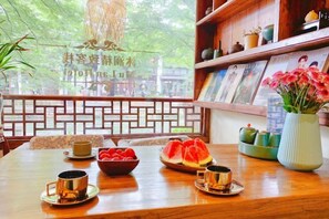 A wooden dining table with a bowl of fruit, teapots, and cups. - Zhouzhuang Latte Play Stone Mulan Hotel (Kunshan)