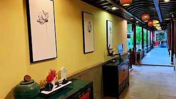 A hallway with framed artwork on the walls, a reception desk, and a decorative vase.
