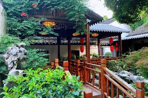 A traditional Chinese courtyard with a wooden pavilion, stone pathway, and lush greenery. - Zhouzhuang Latte Play Stone Mulan Hotel (Kunshan)