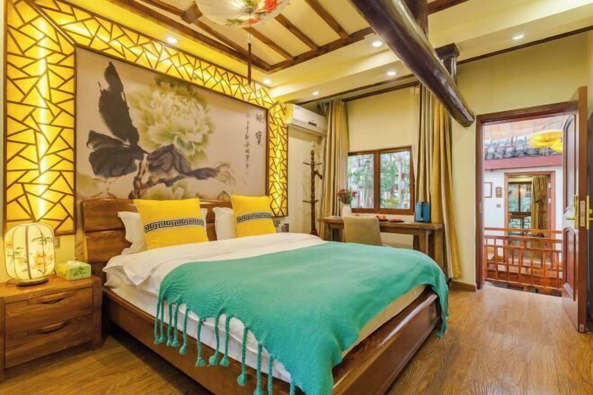 Ein traditionell eingerichtetes Schlafzimmer mit Bett, Nachttisch und einem großen Wandbild.
