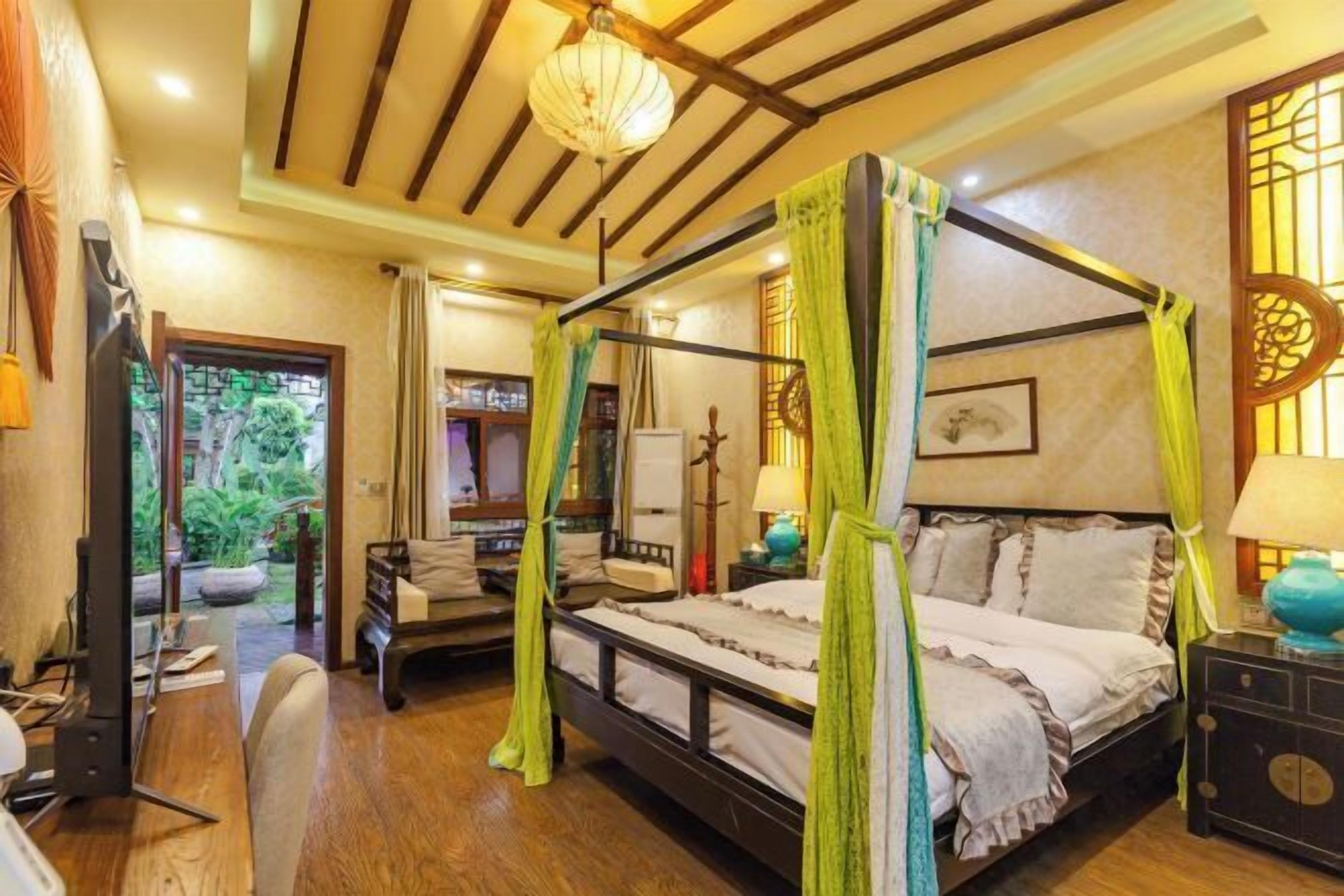 A four-poster bed with a canopy, a desk with a chair, and a television.
