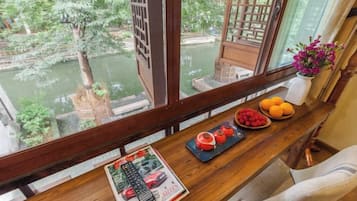 A wooden table with a magazine, remote controls, and fruit.