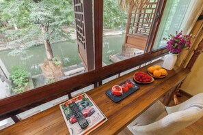 A wooden table with a magazine, remote controls, and fruit. - Zhouzhuang Latte Play Stone Mulan Hotel (Kunshan)