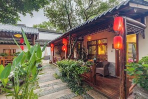 A traditional Chinese-style building with a wooden exterior, red lanterns, and a stone pathway leading to the entrance. - Zhouzhuang Latte Play Stone Mulan Hotel (Kunshan)