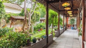 A covered walkway with potted plants and a traditional building in the background. - Zhouzhuang Latte Play Stone Mulan Hotel (Kunshan)