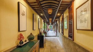 A corridor with framed artwork, a wooden cabinet with decorative items, and a traditional ceiling design. - Zhouzhuang Latte Play Stone Mulan Hotel (Kunshan)