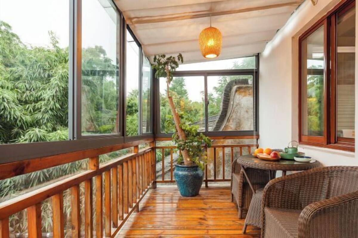 Ein Holzbalkon mit einem Blumentopf, Korbmöbeln und einem Tisch mit Früchten.
