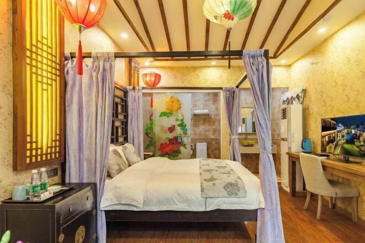 Ein Schlafzimmer mit Bett, Vorhängen, Schreibtisch und Stuhl.