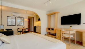 A hotel room with a large bed, a desk with a chair, a TV mounted on the wall, and a small table with chairs. - The Raven Multi Exclusive Trendy 1BR Apartment (Mexico City)
