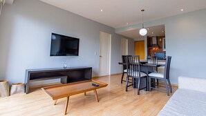 A modern living room with a flat-screen TV, a wooden coffee table, and a dining area with chairs and a table. - City Views Santa Fe I Lovely 1 BR Apartment Within Santa Fe (Mexico City)