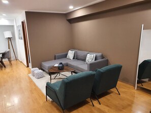 A modern living room with a grey sofa, teal armchairs, and a wooden coffee table. - Michelet Retreat Exclusive Modern 1BR Apartment (Mexico City)