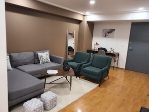 A modern living room with a grey sofa, teal armchairs, a coffee table, and a small white rug. - Michelet Retreat Exclusive Modern 1BR Apartment (Mexico City)