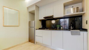 Una cocina moderna con armarios blancos, encimera negra y refrigerador de acero inoxidable.