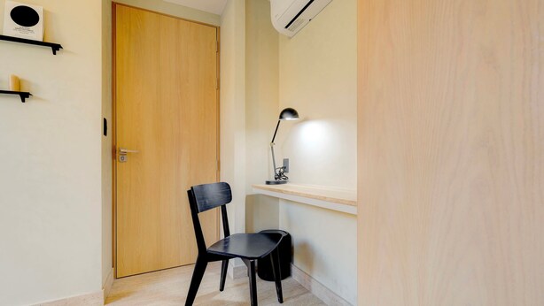 A room with a wooden door, a black chair, a desk with a lamp, and a shelf with a small item. - Aristoteles Elegance Comfort 1 BR Apartment wit (Mexico City)